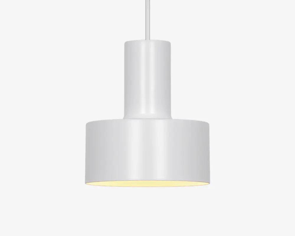 En moderne pendellampe med en glat, mat hvid overflade. Lampen har en cylindrisk øvre del, der går over i en bredere, tromleformet nederdel. Lampeskærmens inderside er let reflekterende, hvilket hjælper med at sprede lyset jævnt. Lampen hænger i en hvid ledning, hvilket giver et rent og minimalistisk udtryk.