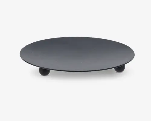 Rund, flad overflade med mat sort finish, hævet af tre små kugleformede fødder. Designet er minimalistisk og moderne med en glat top uden synlige dekorationer. Fødderne giver stabilitet og løfter produktet en smule fra underlaget.