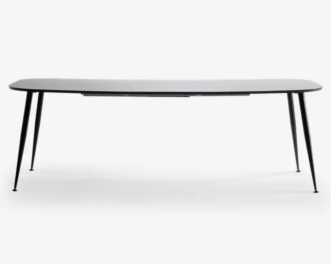 Et moderne bord med en slank, rektangulær hvid bordplade med let afrundede kanter. Bordet understøttes af fire slanke, skråtstillede sorte metalben, hvilket giver det et minimalistisk og nutidigt udseende. Benene er let udadgående for ekstra stabilitet og stil.