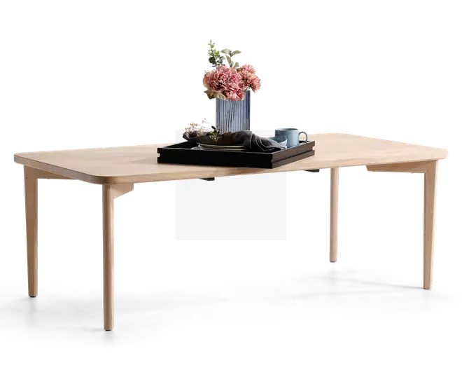 Rektangulært bord med lys træfinish, afrundede hjørner og slanke, tilspidsede ben. Bordpladen er dekoreret med en rillet vase med lyserøde blomster, et sort bakke, en sammenfoldet serviet, en kop med underkop og en lille skål, hvilket giver et moderne og minimalistisk udtryk.