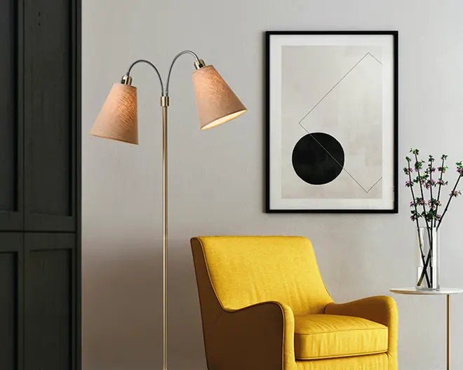 En moderne gulvlampe med to justerbare arme, hver med en kegleformet beige lampeskærm. Lampen har en slank, metallisk stander og et minimalistisk design, der passer til moderne indretning. Skærmene leder lyset nedad, hvilket gør lampen velegnet til læsning eller stemningsbelysning.