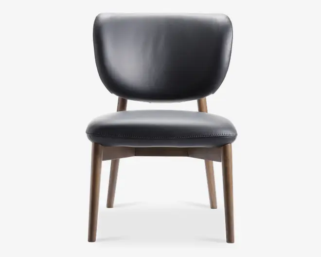 Stol med bred, buet ryglæn og tykt, polstret sæde, begge betrukket med glat sort læder. Benene er lavet af lyst træ med let tilspidsede former, hvilket giver et solidt og stilfuldt fundament. Syninger langs sædets kant tilføjer en diskret dekorativ detalje.