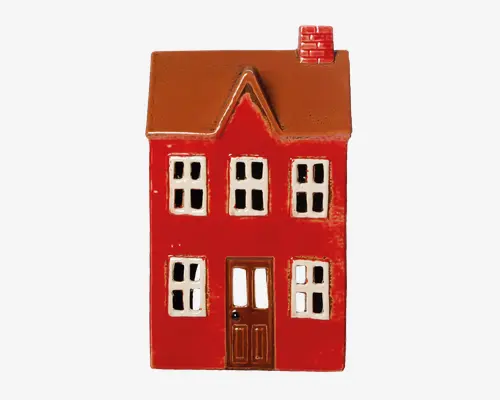 Keramisk ornament formet som et hus, malet i en klar rød farve med brunt tag og en lille skorsten af mursten. Huset har seks vinduer med hvide rammer og sorte ruder, tre på øverste etage og tre på nederste etage, samt en brun dør med vinduespaneler og en lille sort dørknap. Overfladen har en blank finish, hvilket giver den et let reflekterende udseende.