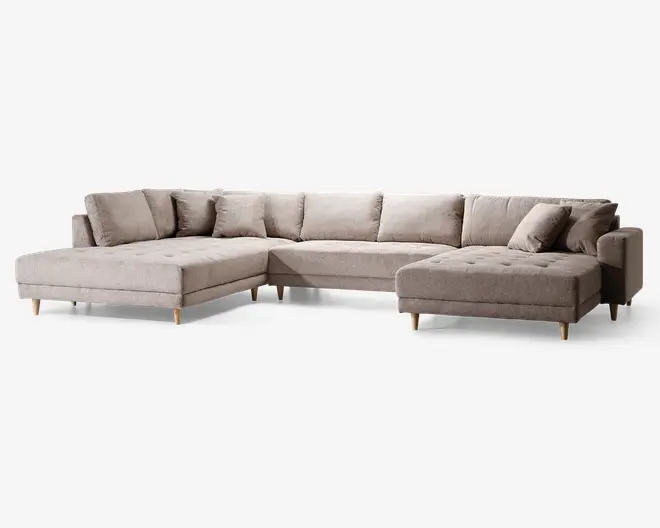Stor L-formet sofa med lyse beige stofbetræk. Har knapdetaljerede sædehynder, flere løse ryghynder for ekstra komfort og skrå træben i naturfarve. Designet inkluderer en chaiselong i den ene ende og et bredt siddeområde, hvilket giver masser af plads til afslapning.