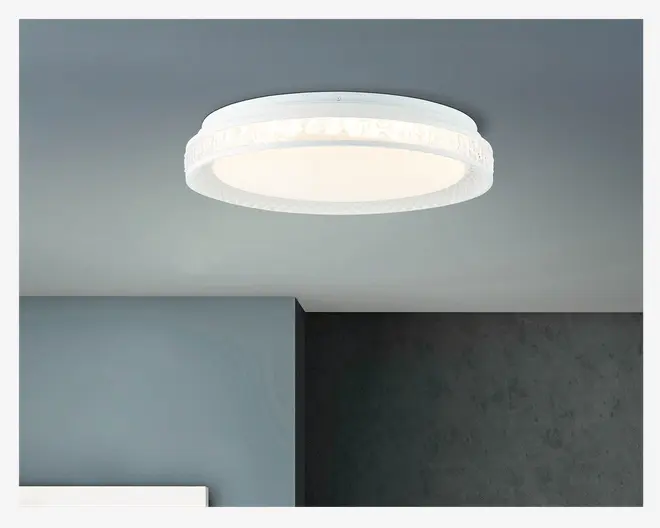 Rund, loftmonteret lampe med en hvid, matteret diffuser, der giver et blødt og jævnt lys. Lampen har en dekorativ, tekstureret kant med et diskret mønster, som tilføjer et elegant præg. Designet er moderne og minimalistisk og passer til mange forskellige rumtyper.