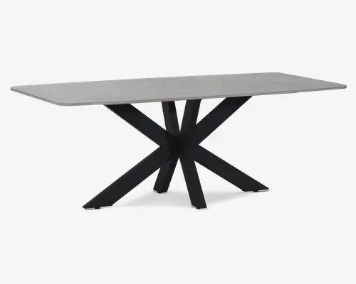 Rektangulært bord med en lys grå, glat bordplade og en markant sort metalbase. Basen har flere skrå ben, der mødes i midten og danner et moderne, stjerneformet design. Bordpladen har rene, lige kanter og et minimalistisk udtryk.