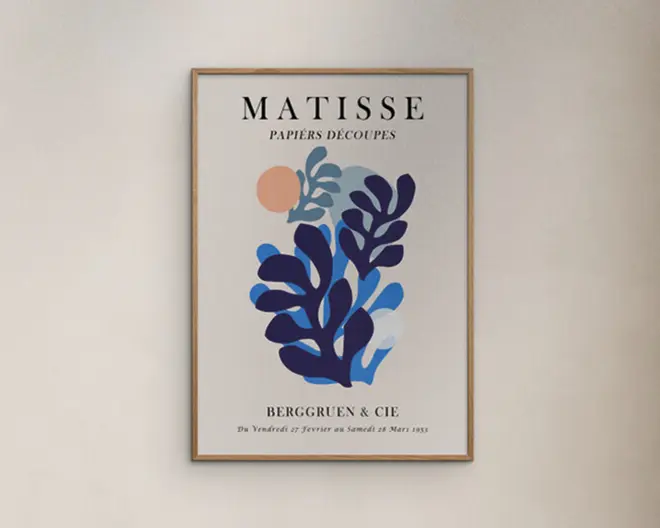 Et indrammet kunsttryk med lys træramme og cremefarvet baggrund, med markante bladlignende former i blå og mørkeblå, en lille ferskenfarvet cirkel øverst samt sort tekst med "MATISSE" og "PAPIERS DÉCOUPÉS".