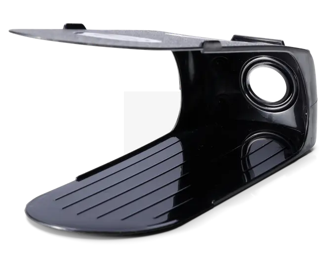 Sort plastkomponent med buet, rillet bund og flad topsektion. Toppen har en metallisk overflade og et cirkulært hul forstærket med en metalring, sandsynligvis til montering eller fastgørelse. Designet har rene linjer og en blank overflade, hvilket tyder på holdbarhed og nem rengøring.