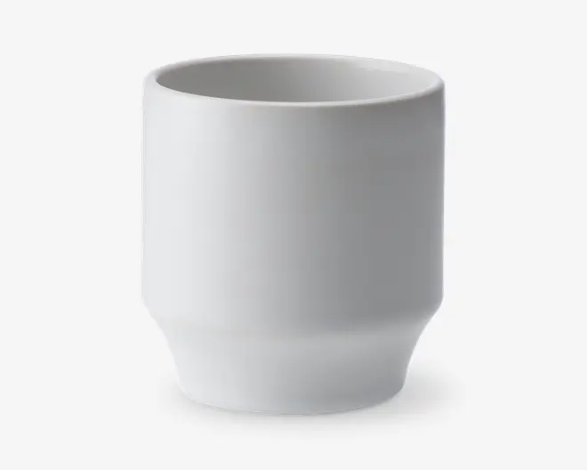 En enkel, hvid keramikkop med en glat, mat overflade. Koppen har en cylindrisk form med lige sider og en let smallere bund, hvilket giver et moderne og minimalistisk udtryk. Der er ingen hank, mønstre eller dekorationer.
