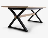 Rektangulært bord med en lys træbordplade og sorte metalben i X-form. Bordet har en matchende lys træstang, der forbinder benene for ekstra stabilitet. Designet er moderne og industrielt med rene linjer og solid konstruktion.