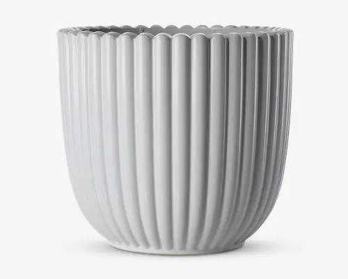 En blank, hvid keramisk beholder med lodrette riller og bølget kant. Designet er moderne og minimalistisk med jævnt fordelte riller, der løber fra bunden til toppen og giver et stilfuldt og elegant udtryk.