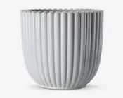 En blank, hvid keramisk beholder med lodrette riller og bølget kant. Designet er moderne og minimalistisk med jævnt fordelte riller, der løber fra bunden til toppen og giver et stilfuldt og elegant udtryk.