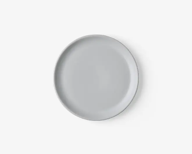 En rund, ensfarvet hvid tallerken med en glat, blank overflade og en let hævet kant. Designet er minimalistisk og moderne, velegnet til både hverdagsbrug og formelle middage.