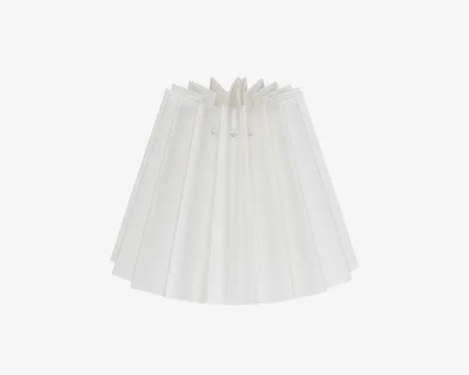 Hvid plisseret lampeskærm med klassisk konisk form. Stoffet er samlet øverst med små dekorative bånd, hvilket skaber jævnt fordelte lodrette folder, der giver skærmen et tekstureret og elegant udtryk. Skærmen er semi-transparent og lader blødt lys trænge igennem materialet.