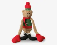 Bamse med lysebrun pels, iført grøn vest med rød kant og hvide knapper, rød halstørklæde, rød og grøn vinterhue med kvast samt store røde vanter og sorte støvler. Bamsen har lange arme og ben, hvilket giver den et sjovt og festligt udtryk.