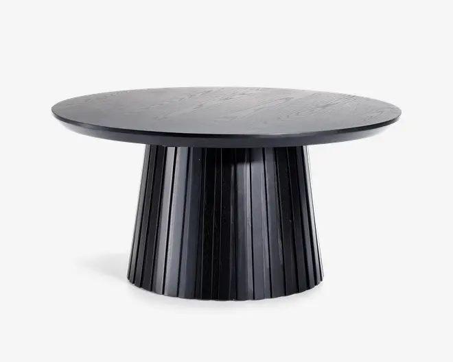 Rundt bord med en glat, flad bordplade og en bred, rillet søjleformet fod. Bordet har en mat sort finish, som giver det et moderne og elegant udtryk. Foden har lodrette riller, der tilføjer struktur og visuel interesse.