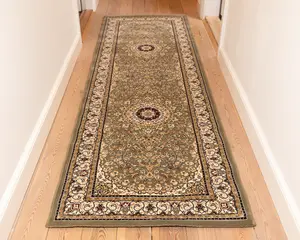 Lang, rektangulær løber med et indviklet blomster- og medaljonmønster i dæmpede grønne, beige og bordeaux nuancer. Tæppet har en detaljeret kant med snoede motiver og små blomsterdetaljer, og midterområdet viser to cirkulære medaljoner. Luvet ser lav ud, og kanterne er pænt afsluttet.