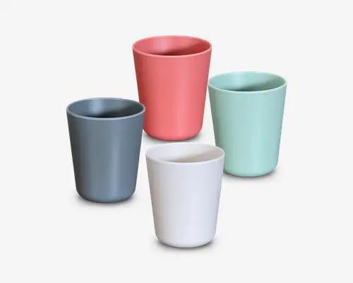 Sæt med fire cylindriske kopper med mat finish, hver i en forskellig farve: koralrød, mintgrøn, skifergrå og offwhite. Kopperne har glatte, afrundede kanter og et minimalistisk design uden hank eller synlige mønstre.