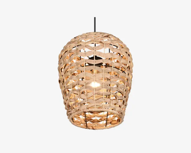 Hængelampe med en håndflettet lampeskærm i natur-rattan, formet som en rund, let aflang kurv. Det åbne fletmønster lader lyset skinne igennem og skaber en varm og hyggelig stemning. Lampen hænger i en sort ledning, og pæren er synlig gennem fletværket, hvilket giver et rustikt og organisk udtryk til rummet.
