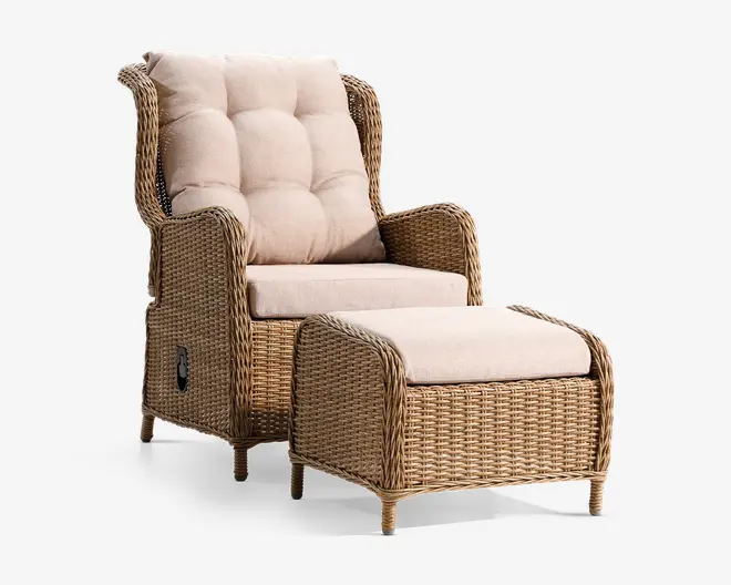 Højrygget stol og matchende skammel fremstillet af flettet rattan med naturfarvet finish. Stolen har tykke, quiltede beige hynder på sæde, ryg og hovedstøtte for ekstra komfort. Armlænene er brede, og stolen har et sidehåndtag, hvilket indikerer en tilbagelænet funktion. Skamlen har en matchende flettet ramme og en flad, polstret top til benstøtte.