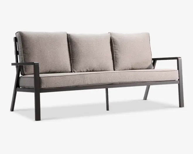 Moderne tresæders sofa med en robust, mat sort metalramme og armlæn. Sofaen har tykke, lyse beige hynder på både sæde og ryg, hvilket giver en komfortabel og støttende siddeoplevelse. Designet er minimalistisk og moderne, velegnet til både indendørs og udendørs brug.