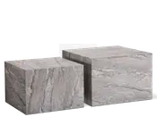 Sæt med to kubeformede borde lavet af grå marmor med naturlige årer. Bordene har en glat, poleret overflade og et minimalistisk, blokagtigt design. Det ene bord er lidt højere og større end det andet, så de kan placeres sammen eller ved siden af hinanden. Marmormønsteret varierer på hver flade, hvilket giver et unikt og elegant udtryk.