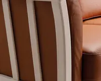 Nærbillede af et møbel med glat, lysebrunt læderbetræk og en ramme af lyst træ. Læderet ser blødt og velpolstret ud med synlige syninger langs kanterne. Trærammen har en naturlig finish og lodrette lameller, hvilket giver et moderne og solidt udtryk.