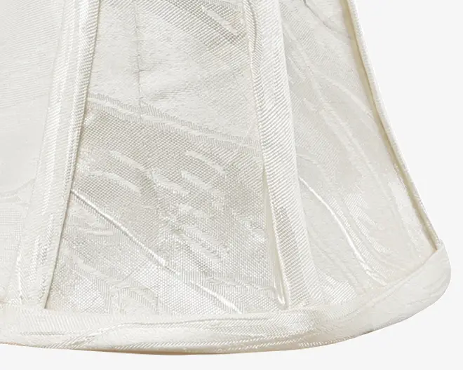 Elfenbensfarvet stof med diskret blomster jacquardmønster, struktureret med lodrette stofbeklædte ribber og afsluttet med matchende kantbånd foroven og forneden. Stoffet har en let glans, hvilket giver et elegant udtryk.