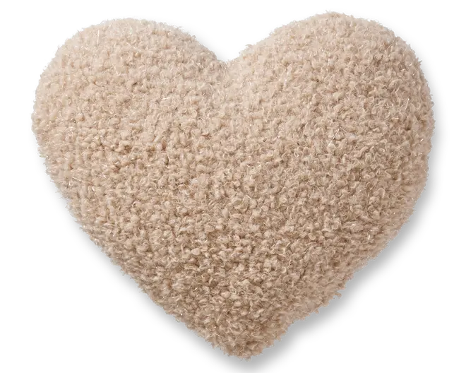 Hjerteformet pude med et blødt, tekstureret bouclé-stof i en lys beige farve. Overfladen fremstår fluffy og hyggelig, hvilket giver en blød og behagelig fornemmelse. Puden er fyldig og velpolstret, hvilket gør den velegnet til dekoration eller komfort.