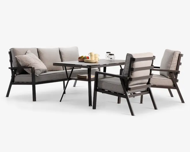 Dette sæt har et moderne udendørs siddearrangement med et rektangulært spisebord, en to-personers bænk og to lænestole. Stellet er lavet af mørkt metal med rene, kantede linjer, og sæder samt rygge er udstyret med tykke, lysegrå hynder for ekstra komfort. Den ene lænestol har et lameldesign på ryggen, og bænken inkluderer en dekorativ pyntepude. Bordpladen er rummelig og egnet til spisning eller underholdning, og det samlede udtryk er moderne og indbydende.