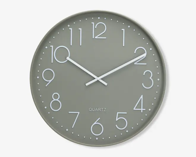 Rund vægur med matgrå urskive og hvide minimalistiske tal. Uret har slanke hvide time- og minutvisere og et enkelt design uden sekundviser. Små hvide prikker markerer hvert minut langs kanten. Ordet 'QUARTZ' er trykt over klokken 6-positionen.