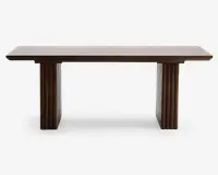 Rektangulært bord med en glat, flad bordplade i træ og to brede, lodrette ben. Benene har et rillet design med lodrette riller, hvilket giver et dekorativt udtryk. Træet har en mellembrun finish, som giver bordet et moderne og elegant udseende.