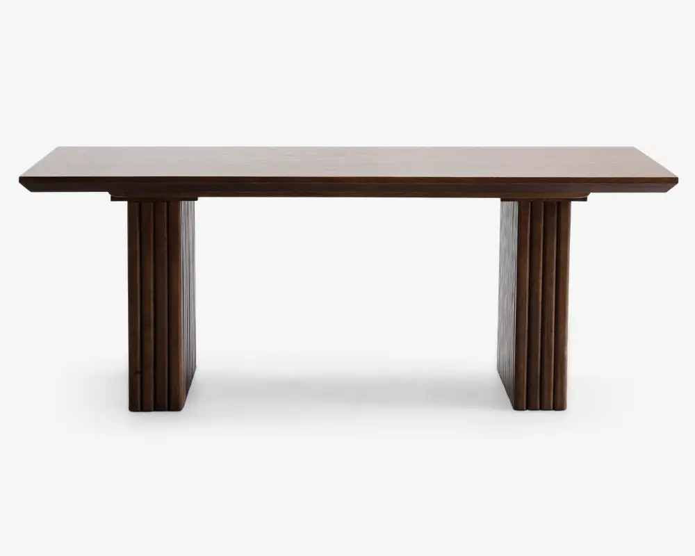 Rektangulært bord med en glat, flad bordplade i træ og to brede, lodrette ben. Benene har et rillet design med lodrette riller, hvilket giver et dekorativt udtryk. Træet har en mellembrun finish, som giver bordet et moderne og elegant udseende.