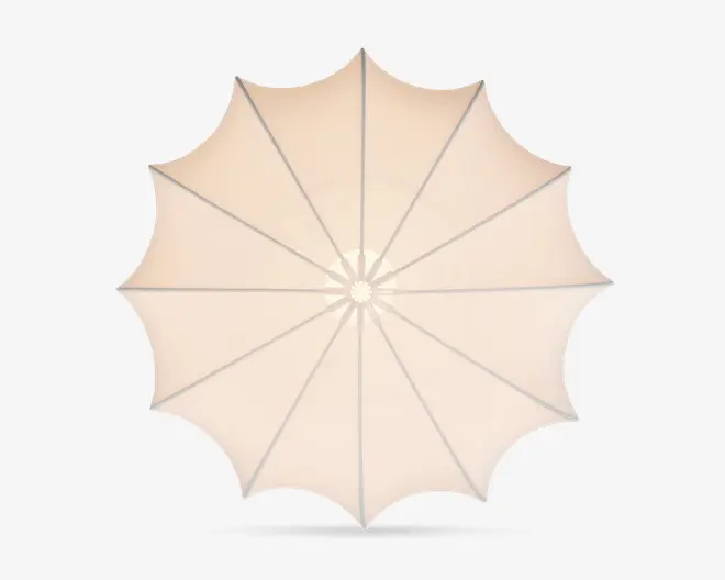 Set ovenfra af en stor, rund udendørs parasol med beige stofdug. Dugen er opdelt i tolv sektioner af jævnt fordelte støtteben, hvilket skaber et symmetrisk, stjernelignende mønster. Stoffet er stramt spændt ud, og kanten har en let bølget, dekorativ finish.