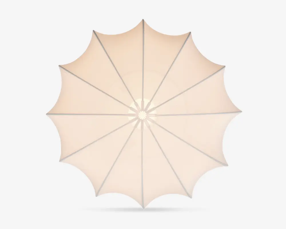 Set ovenfra af en stor, rund udendørs parasol med beige stofdug. Dugen er opdelt i tolv sektioner af jævnt fordelte støtteben, hvilket skaber et symmetrisk, stjernelignende mønster. Stoffet er stramt spændt ud, og kanten har en let bølget, dekorativ finish.