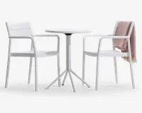 Sættet består af to hvide stole med armlæn og et matchende rundt bord. Stolene har et moderne, minimalistisk design med let buede ryg- og sædeflader. På den ene stol hænger et tekstureret, lysebrunt tæppe over ryglænet. Bordet har en slank, rund bordplade og en solid base med fire ben.