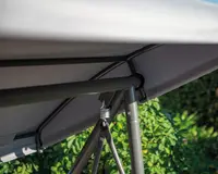 Nærbillede af en solid metalramme med en fjeder-mekanisme, der understøtter et gråt stofovertræk. Rammen har skrå støttebøjler og sikre samlinger, designet for stabilitet og holdbarhed. Stoffet ser ud til at være vejrbestandigt og egnet til udendørs brug.