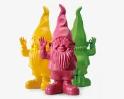 Tre dekorative nissefigurer vises, hver med en blank, ensfarvet overflade. Nisserne har lange skæg, spidse hatte og vinker med højre hånd. Den forreste nisse er lyserød, den bagved er gul, og den bagerste er grøn. Alle tre har et muntert, venligt udtryk og et moderne, minimalistisk design med glatte overflader uden ekstra detaljer.