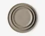 Sæt med tre runde tallerkener i forskellige størrelser, alle i en mat taupe-farve. Tallerkenerne har et enkelt, minimalistisk design med glatte overflader og let hævede kanter. De er stablet pænt fra den mindste til den største, hvilket viser størrelsesforskellen.