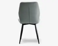 Billedet viser bagsiden af en stol med et glat, lysegråt polstret ryglæn, der har en lodret syning i midten. Stolen har slanke, sorte metalben, der er let udadskrånende for stabilitet. Betrækket ser ud til at være af blødt stof, og designet er moderne og minimalistisk.