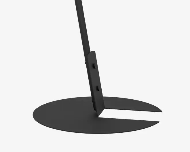 Nærbillede af en mat sort metalbase med cirkulær form og et udskåret område, hvor en lodret støtte er fastgjort med synlige slidser. Designet er robust og minimalistisk, velegnet til stabil placering på flade overflader.