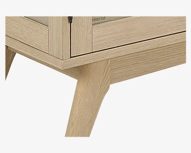 Nærbillede af et lyst træskabsben med skråt, tilspidset design. Skabet har en glat, naturlig træstruktur og en glaslåge med sort hængsel. Konstruktionen fremstår solid og moderne med rene linjer og et minimalistisk udtryk.