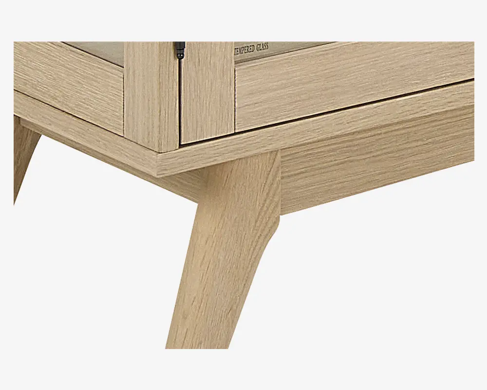 Nærbillede af et lyst træskabsben med skråt, tilspidset design. Skabet har en glat, naturlig træstruktur og en glaslåge med sort hængsel. Konstruktionen fremstår solid og moderne med rene linjer og et minimalistisk udtryk.