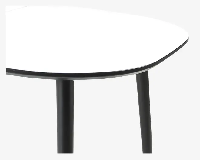 Nærbillede af et bordhjørne, der viser en glat, hvid bordplade med en tynd sort kant. Bordpladen har en afrundet, let skrå form. Bordet understøttes af solide, cylindriske sorte metalben.