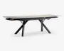 Rektangulært bord med en lys, glat bordplade og sorte, skråtstillede metalben, der er arrangeret i et X-mønster i hver ende. Bordet har et moderne, minimalistisk design med rene linjer og en solid ramme, velegnet til spise- eller arbejdsbrug.