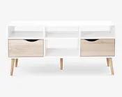 Rektangulær hvid opbevaringsenhed med fire skråtstillede ben i lyst træ, to rummelige skuffer i lyst træ med buede sorte udskæringer som greb, tre åbne hylder over skufferne samt en central åben hylde til ekstra opbevaring eller udstilling.