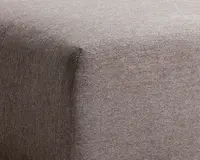 Nærbillede af hjørnet på et møbel betrukket med blødt, taupefarvet stof. Stoffet har en glat, fløjlsagtig tekstur og er stramt tilpasset rundt om kanterne, hvilket giver et rent og moderne udtryk.