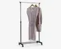 Et fritstående tøjstativ i metal med blank kromfinish. Stativet har en vandret bøjlestang understøttet af to lodrette stolper og står på en base med fire hjul, så det er nemt at flytte. Der hænger to stykker tøj på træbøjler: en lysefarvet, langærmet kjole med diskret blomstermønster og en beige, langærmet cardigan med store forlommer. Stativet har et enkelt, minimalistisk design, der egner sig til organisering eller fremvisning af tøj.