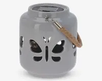 En rund, blank keramiklanterne med udskårne sommerfugleformer på siderne. Den har et robust rebhåndtag fastgjort med metalbeslag og et solpanel på toppen til opladning. Indvendigt ses en lille pære gennem udskæringerne, som er designet til at skabe dekorative lysmønstre, når lanternen er tændt.