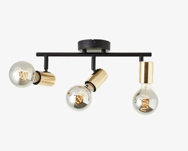 Loftmonteret lampearmatur med tre synlige runde pærer, hver fastgjort i en cylindrisk fatning i guldfarve. Pærerne er placeret på en vandret sort metalstang, hvor hver fatning er vinklet i forskellige retninger for justerbar belysning. Armaturet har et moderne, industrielt design med synlige glødetråde i pærerne og en mat sort, rund base til montering.